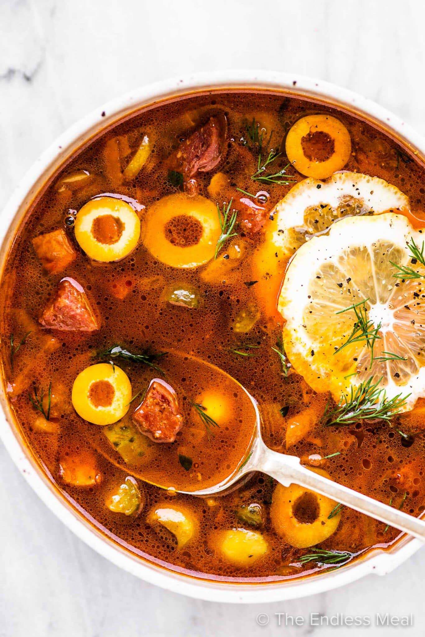 Solyanka (Солянка) - Hearty soup with mixed meats, pickles, and olives. Rich, tangy, and deeply satisfying.